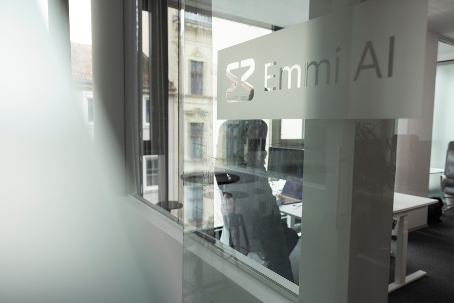 Glass wall in office with logo and lettering Emmi AI © Emmi AI